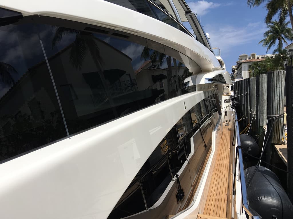 Curved yacht windshield with reflective marine film and teak side deck
